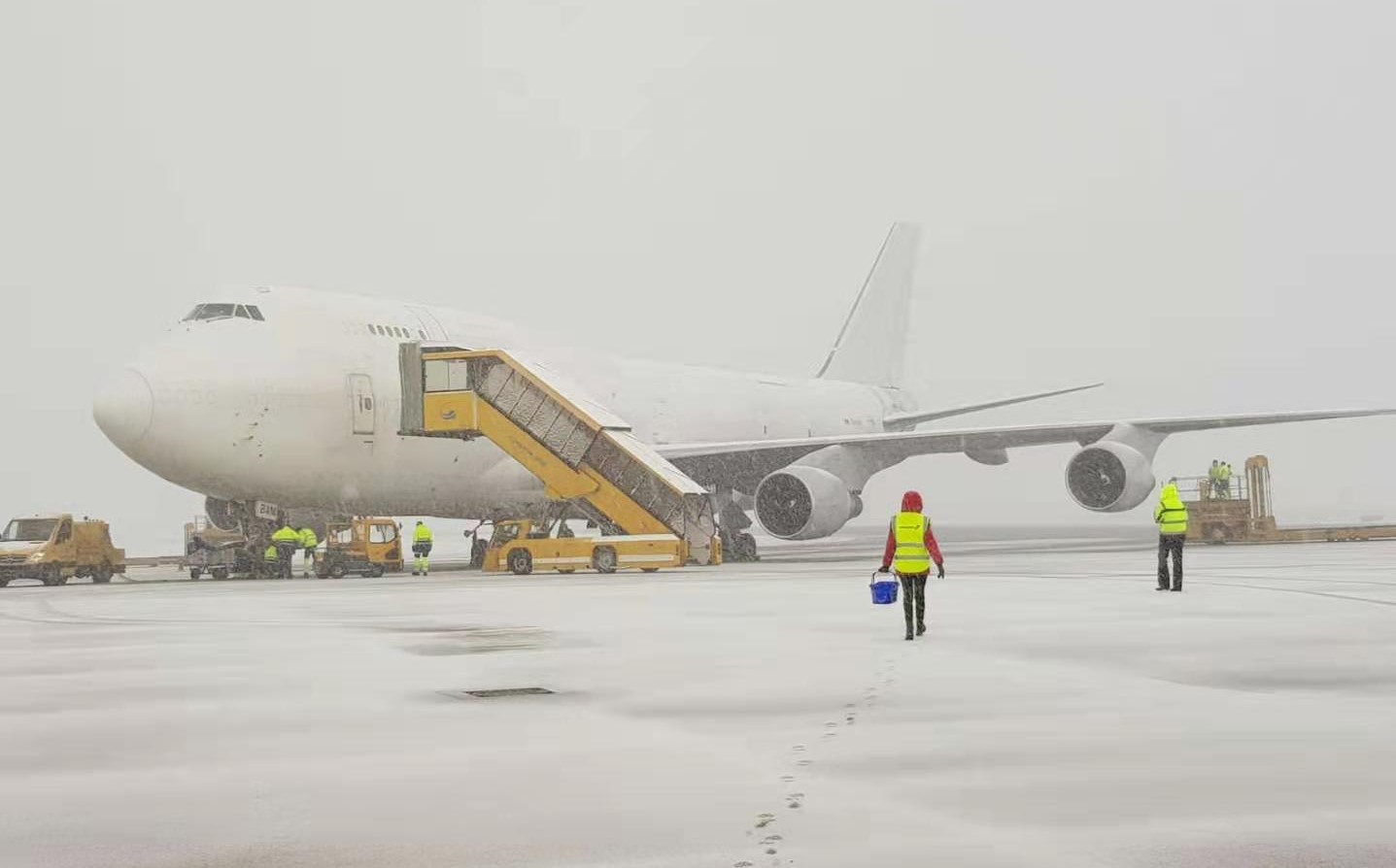 aircraft in snow at airport with yellow stairs