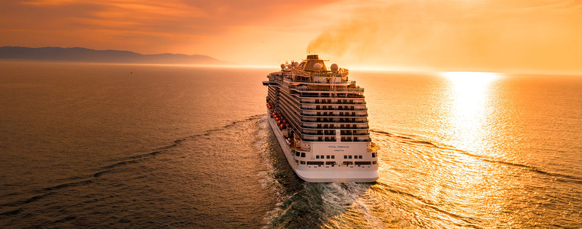 un crucero navega hacia la puesta de sol.