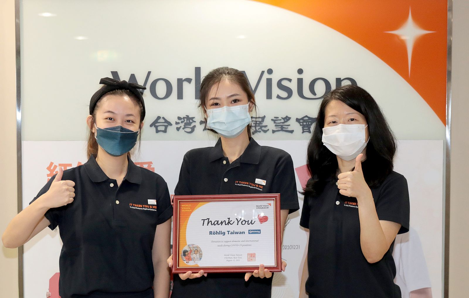 Three representatives hold Rohlig Taiwan donation certificate in front of World Vision logo. 